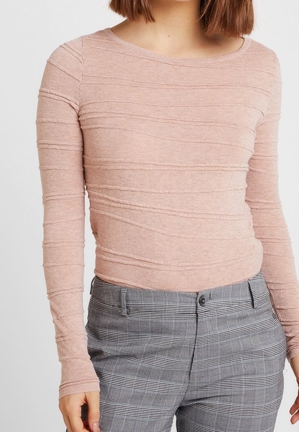 Ljust rosa långärmad tröja med texturerade horisontella ränder, kombinerad med grå rutiga byxor med knappstängning och fickor.