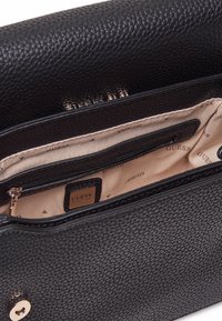 Borsa in finta pelle nera con interno crema. Presenta una tasca con zip e una placca del marchio in oro. Chiusura con bottone a calamita.