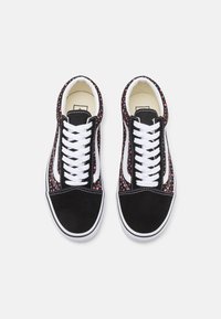 Baskets noires et rouges avec un embout en daim noir, des lacets blancs, une doublure intérieure florale et une bande latérale blanche. Semelle en caoutchouc plate.