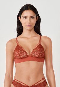 Rode kanten bralette met een driehoekige vorm, voorzien van verstelbare bandjes en ronde hardwareaccenten. De gladde onderband biedt ondersteuning.