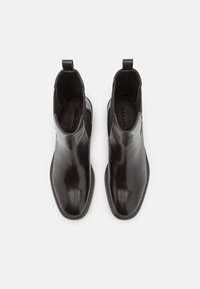 Botines negros de cuero con acabado suave, paneles laterales elásticos y suela de goma texturizada. Punta redondeada y tiradores para facilitar su uso.