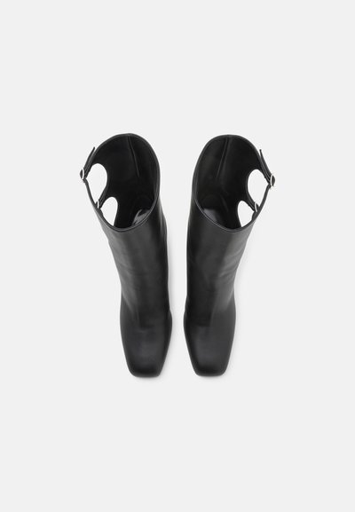 Black leather knee-high boots with smooth texture, pointed toe, and cutout accents at the top. Includes a small buckle detail.