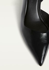 Pump nera a punta con tomaia in sintetico texture e interno liscio, caratterizzata da una silhouette elegante senza decorazioni.