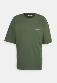 Oliwkowa bawełniana koszulka z luźnym krojem, okrągłym dekoltem, krótkimi rękawami i małym białym logo po lewej stronie klatki piersiowej.