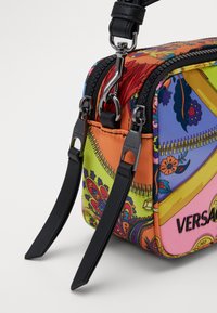 Pestrobarevná obdélníková taška s textilním vzorovaným povrchem, černými koženými popruhy a stříbrnými detaily. Disponuje dvojitým zipem pro uzavření.