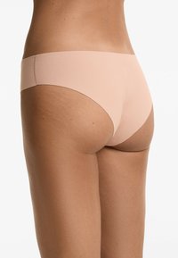 Naadloze huidskleurige ondergoed met een lage taille, gemaakt van zachte stof, met een eenvoudige snit en gladde randen voor minimale zichtbaarheid.