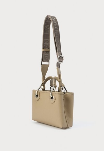 Μπεζ δερμάτινη τσάντα χειρός με δύο επάνω λαβές και αποσπώμενο ιμάντα ώμου. Διαθέτει μεταλλικές λεπτομέρειες και ανάγλυφη υφή.
