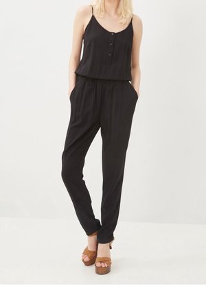 Sort jumpsuit med spaghettistropper, knaplukning foran, elastisk talje og sidelommer. Kombineret med brune platåsandaler.