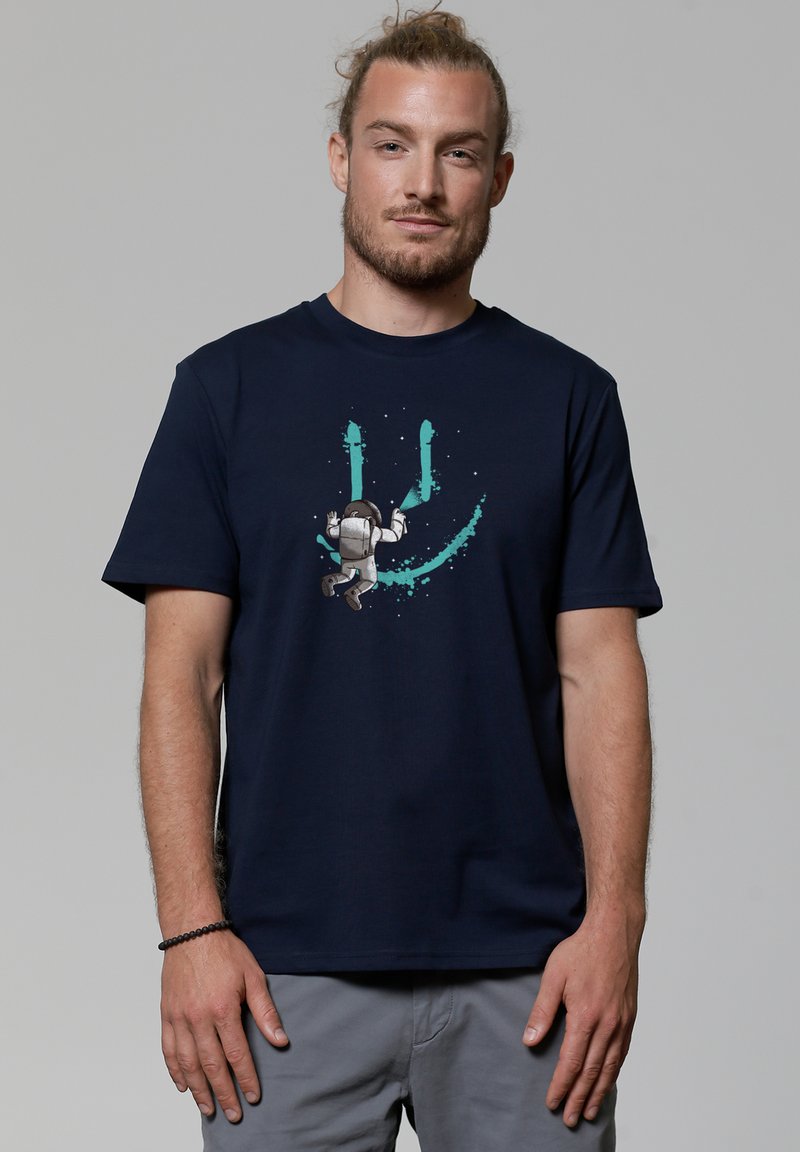 Navyblauwe katoenen t-shirt met een afbeelding van een astronaut met turquoise spetters en een glimlachend gezicht ontwerp. Korte mouwen en ronde halslijn.