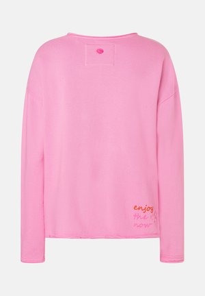 Rosa Langarm-Sweatshirt mit überschnittenen Schultern, gesticktem rechteckigen Patch in der Nähe des Halsausschnitts und "enjoy the now" in Schreibschrift am unteren rechten Rücken bestickt.