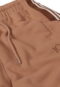 Joggers marron clair en tissu doux, avec une taille à cordon de serrage aux embouts métalliques, et des bandes latérales en marron foncé et blanc.
