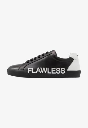 Černé nízké tenisky s bílým podpatkem a velkým bílým nápisem "FLAWLESS" na boku, s černými tkaničkami a černou podrážkou.