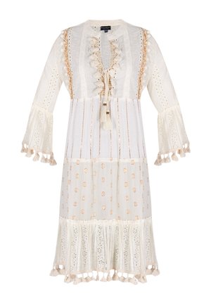 Robe blanche avec un col rond, un devant à volants et des accents de pompons. Présente une bordure en dentelle et des motifs à pois, avec des manches évasées.