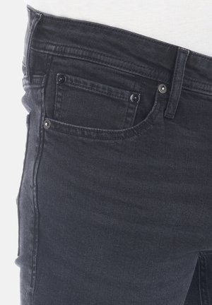 Jeans in denim nero con un classico design a cinque tasche, caratterizzati da hardware in metallo argentato e una texture leggermente sbiadita sul tessuto.