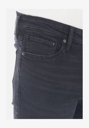 Schwarze Denim-Jeans mit einem klassischen Fünf-Taschen-Design, ausgestattet mit silbernem Metallzubehör und einem leicht abgenutzten Textur auf dem Stoff.