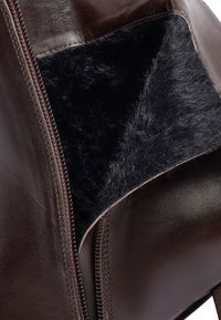 Brown leather bag with a plush black interior, featuring a smooth exterior and a visible zipper along the opening.