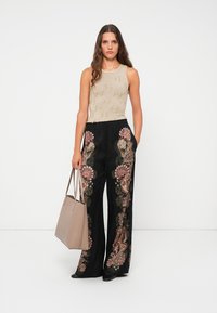 Beige knitted sleeveless top paired with black wide-leg pants featuring colorful floral embroidery. Accessories include a light beige tote bag.