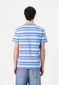 Camiseta de rayas azul con rayas horizontales rojas y blancas, material de algodón, cuello redondo, mangas cortas y dobladillo recto.
