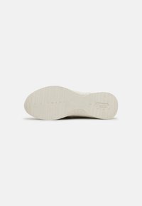 White sneaker sole with textured grip pattern and logo. Rounded shape, made of rubber for durability and traction. Smooth finish.