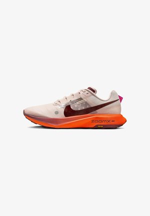 Chaussure de course Nike light beige et orange avec un grand swoosh noir, une semelle épaisse et la marque "ZoomX" sur le côté.