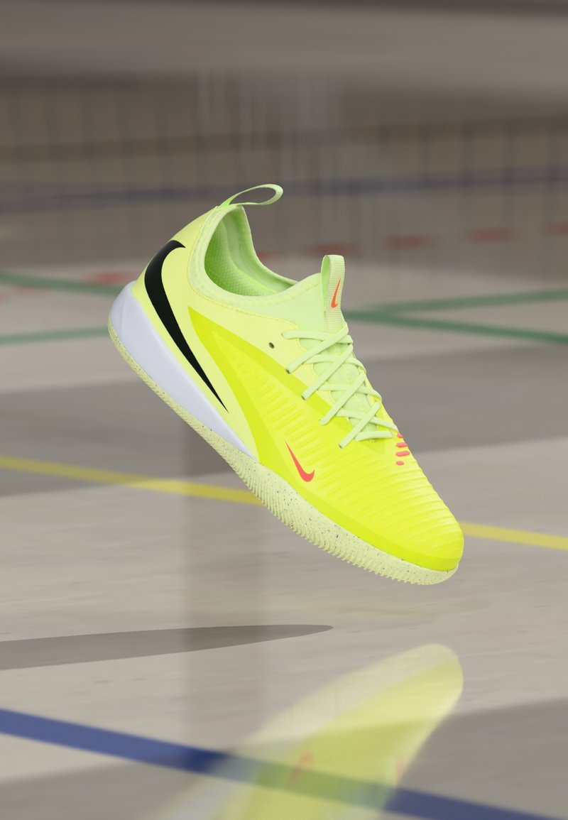 Neonowo-żółty but sportowy z teksturowaną cholewką, czarnymi akcentami i białą podeszwą. Posiada sznurowanie oraz tylną pętlę ułatwiającą zakładanie.