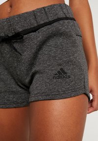 Shorts deportivos grises con una tela texturizada, cintura elástica y un cordón negro. Logo de Adidas en negro en el dobladillo.