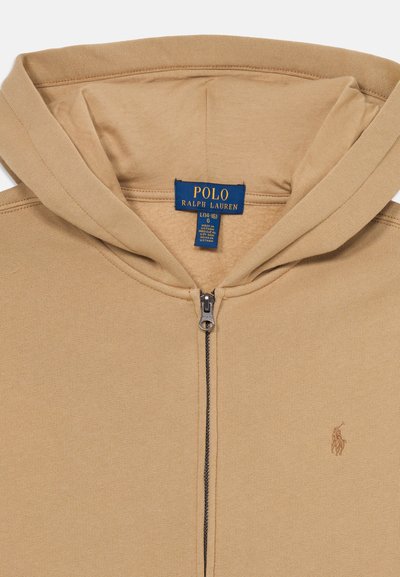 Beige Kapuzenzip-Jacke aus weichem Stoff mit dezentem Logo-Stick auf der Brust und einem metallenen Reißverschluss.