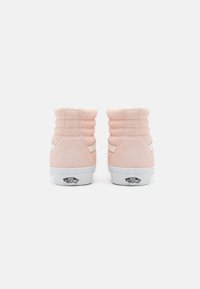 Roosa sametist kõrge lõikega sneakers valgete aktsentidega, karvane krae ja logo kandadel. Külgmised õmblused lisavad tekstuuri ja kujunduse detaili.