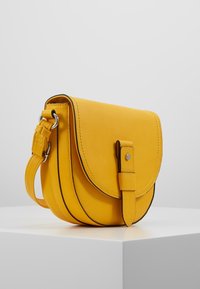 Borsa a tracolla in pelle gialla con un patta arrotondata, chiusura anteriore a fibbia e una tracolla metallica regolabile. Presenta una texture liscia e bordi cuciti.