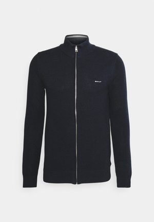 Navy-blauer Zip-Pullover mit strukturiertem Strickmuster, hohem Kragen und gerippten Bündchen. Mit einem kleinen Logo auf der Brust.
