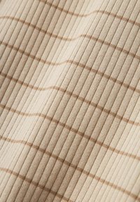Beige bordázott szövet, puha tapintással, barna kockás mintával. A vonalak finom hullámokat hoznak létre az anyagon.