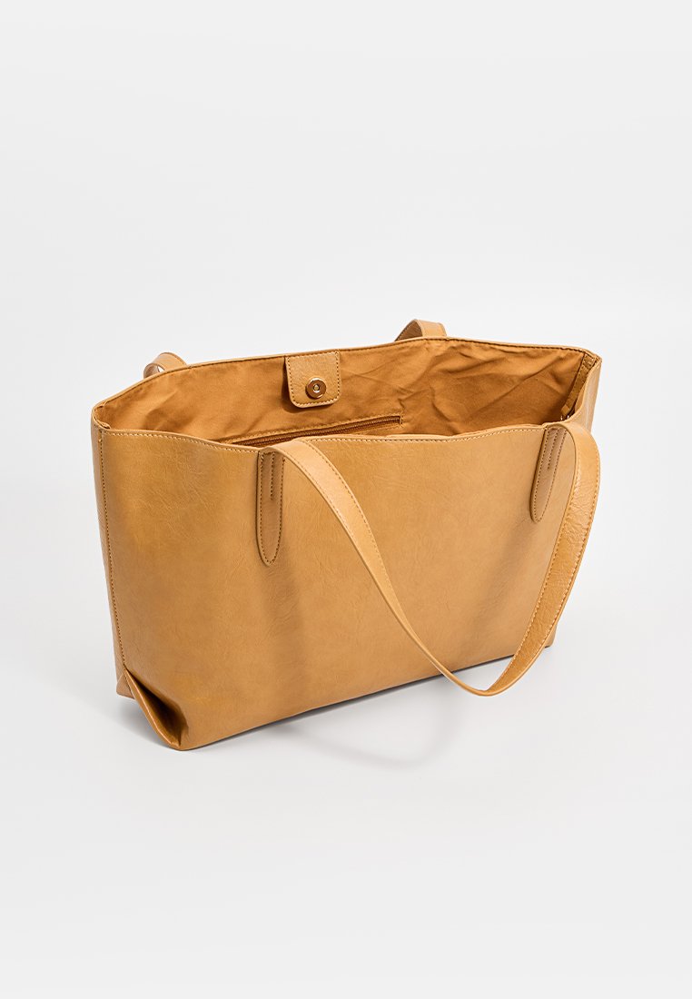 Sac fourre-tout en cuir tan avec une texture lisse, de forme rectangulaire et à longues poignées ; doté d'une fermeture à pression et d'un intérieur uni.
