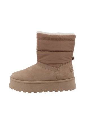 Botte d'hiver beige avec semelle épaisse, partie supérieure rembourrée et doublure intérieure douce conçue pour la chaleur et le confort.