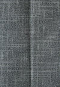 Tissu gris tissé avec un motif quadrillé fin, présentant une texture lisse et un léger éclat, adapté pour les vêtements ou le rembourrage.