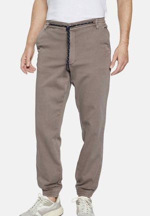 Light brown jogger pants with an elastic waistband and drawstring. Features tapered cuffs and side pockets, made from a soft fabric.