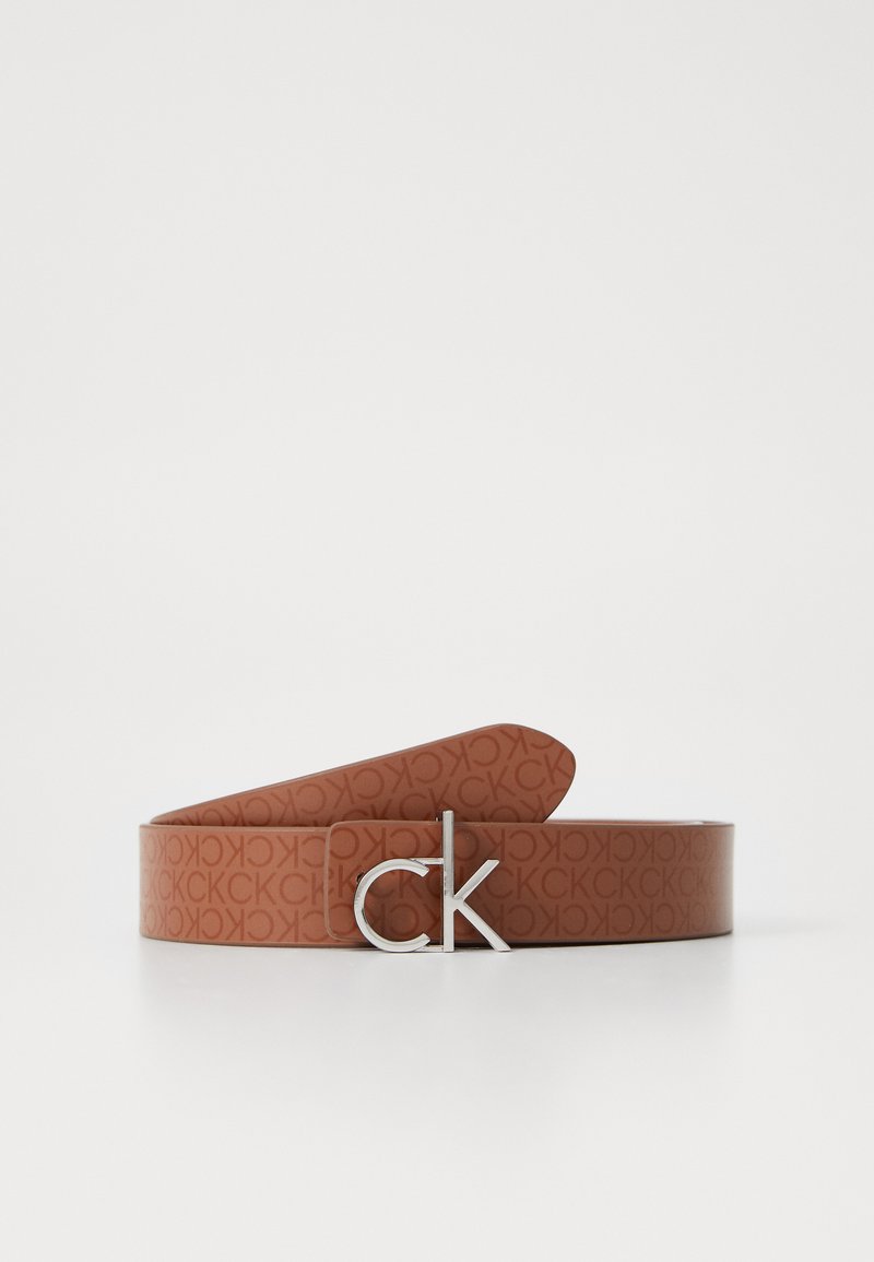Hnedý monogramový opasok s strieborným logom "ck". Vyrobený z hladkého syntetického materiálu s plochým, obdĺžnikovým tvarom.