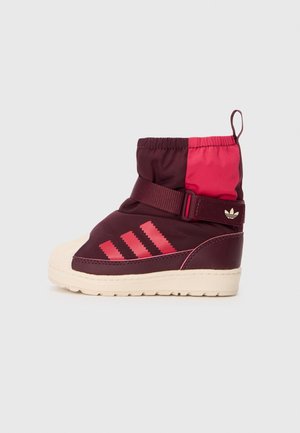Baskets montantes pour enfant bordeaux et rose avec semelle blanche, fermeture par bride et trois bandes roses Adidas sur le côté.