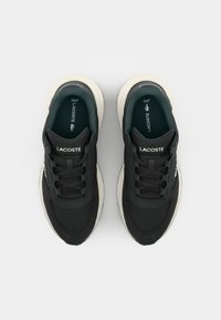 Black athletic sneakers with padded tongue and collar, textured upper, and white sole. Branding visible on the tongue and side.