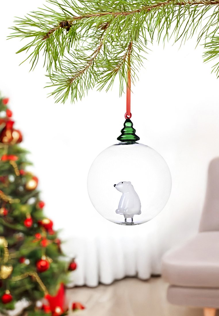 Klarer Glasornament mit einem grünen und roten Deckel. Innen sitzt ein weißer Eisbär, umgeben von einer glatten Glasoberfläche.