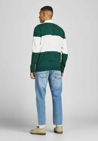 Suéter a rayas verde y blanco con cuello, combinado con jeans azul claro y zapatos beige. La textura parece de punto y es relajada.
