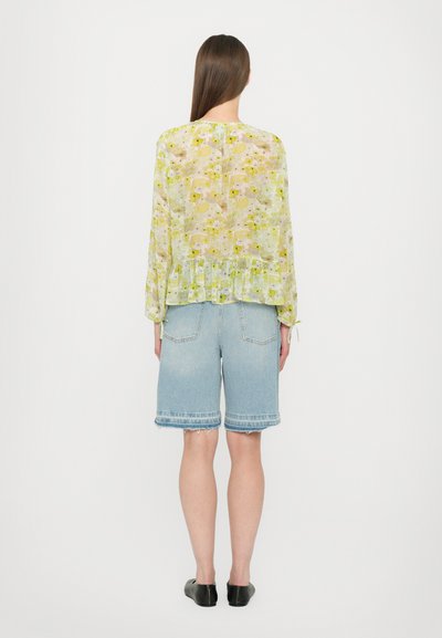 Sheer, floral-patterned blouse in light green tones, paired with light blue denim shorts, featuring frayed hems and a relaxed fit.