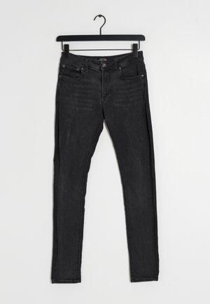 Czarne dżinsy z wąskim krojem. Posiadają pięć kieszeni, guzikowy zamek i szlufki na pasek. Tekstura pokazuje lekkie blaknięcie i zużycie.