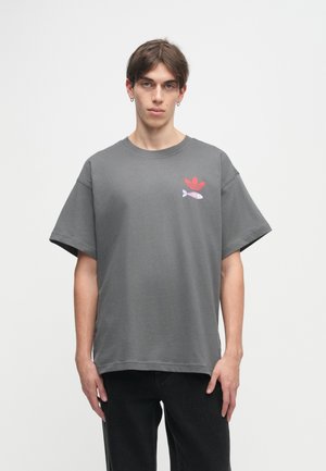 Γκρι κοντομάνικο μπλουζάκι φτιαγμένο από βαμβάκι, με κόκκινο λογότυπο και γραφικό ενός ψαριού στην αριστερή πλευρά, με χαλαρή, τετράγωνη εφαρμογή.