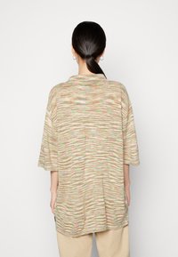 Top de malha oversized com uma palete de cores pastéis suaves, apresentando um padrão em forma de onda. Gola descontraída e mangas curtas, proporcionando um ajuste solto.