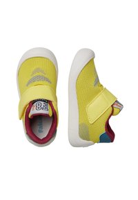 Baskets en mesh jaune avec une semelle en caoutchouc blanche, dotées d'une lanière en velcro et d'accents bordeaux. Comprend un motif texturé sur le côté.