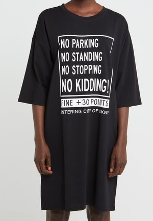 Czarna, oversize sukienka T-shirt z białym napisem "Zakaz parkowania, zakaz postoju, zakaz zatrzymywania się, bez żartów! Grzywna +30 punktów. Wjazd do miasta DKNY."
