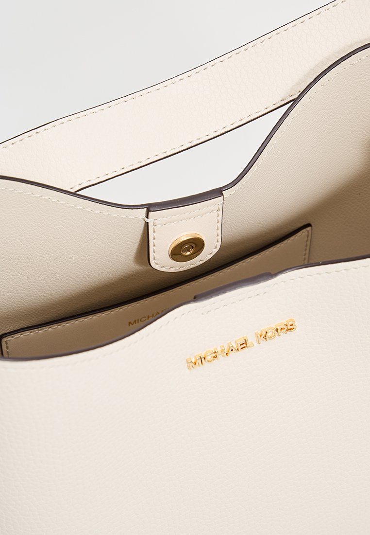 Borsa a tote in pelle beige con apertura superiore, caratterizzata da una chiusura a scatto dorata e nome del marchio in rilievo. Texture liscia con un design minimalista.
