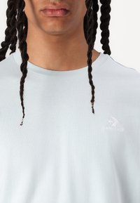 Himmelblaues Baumwoll-T-Shirt mit Rundhalsausschnitt und kurzen Ärmeln. Mit dezentem weißen, gesticktem Converse-Logo auf der Brust.