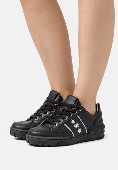 Sneaker nere in pelle perforata, con dettagli argentati e stelle. Presentano lacci neri e una suola in gomma con battistrada strutturato.