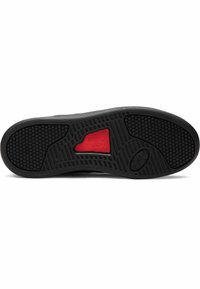 Black rubber shoe sole with textured grip patterns. Red Under Armour logo featured prominently on the sole’s side. Flat, well-defined edges.